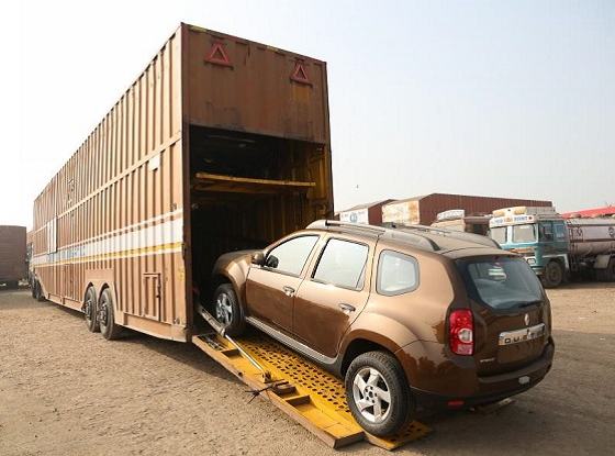 Car being driven up a ramp into an enclosed car carrier